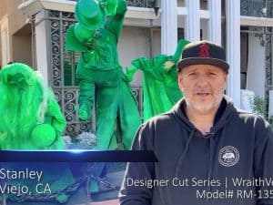 Outdoor projector screen with a man and green street performers in the background.