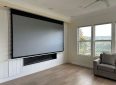 Large motorized projector screen in a bright living room setting.