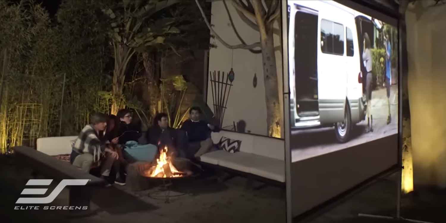 Outdoor projector screen setup with a vehicle and a group of people.