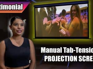 Woman giving testimonial in front of Elite Screens Manual Tab-Tension 2 projection screen.
