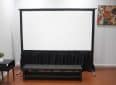Projector screen with black casing and stand in a modern room.