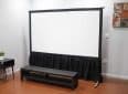 Elite Screens projector screen with black frame and stand in a modern room.