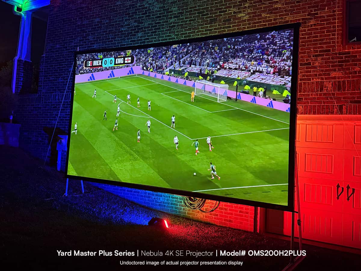 Large outdoor projector screen displaying a soccer match at night.